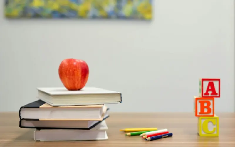 Books, an apple and alphabet blocks on a desk